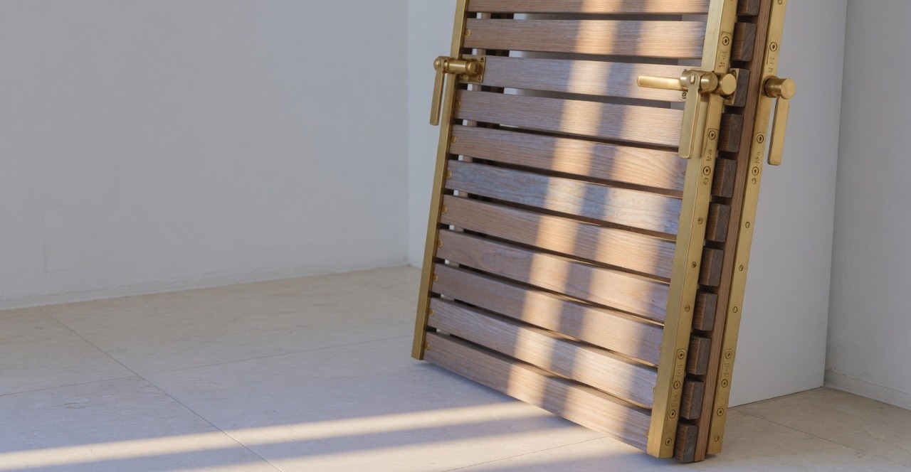 A timber and brass louvre panel in raking gallery light.